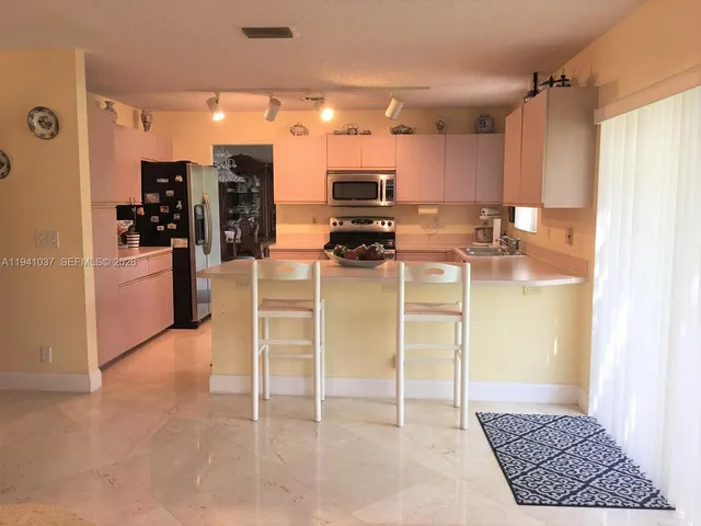 a kitchen with stainless steel appliances kitchen island granite countertop a refrigerator and microwave