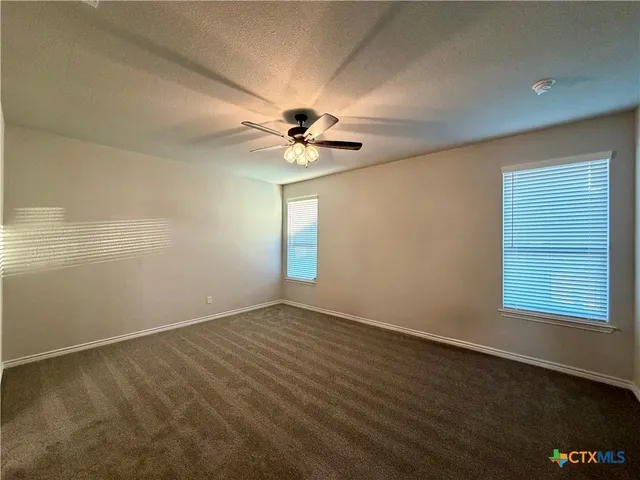 an empty room with a window and a ceiling fan