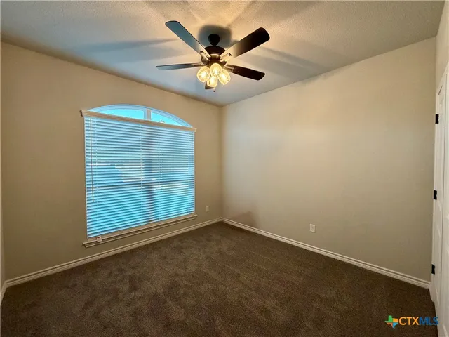 an empty room with window and ceiling fan