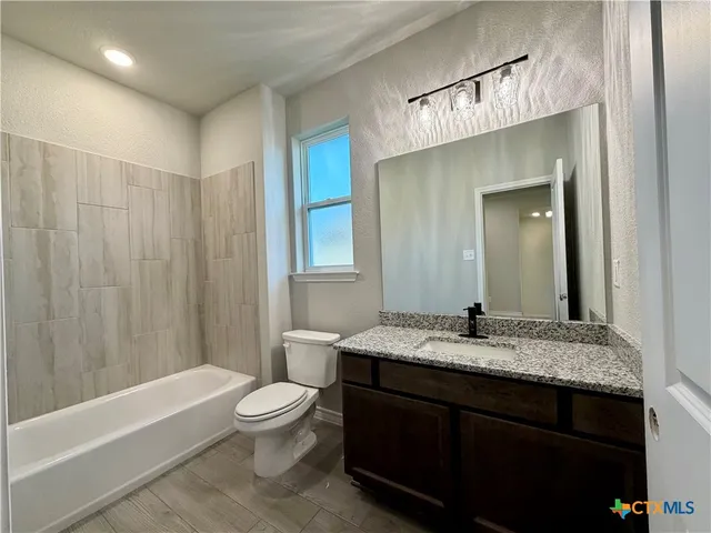 a bathroom with a granite countertop sink toilet a large mirror a bathtub and shower