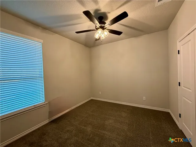 an empty room with a ceiling fan and a window