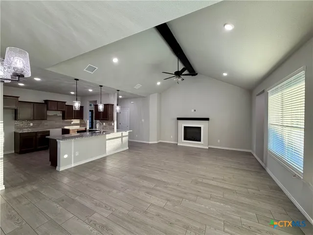 a large kitchen with a large counter top a sink stainless steel appliances and cabinets