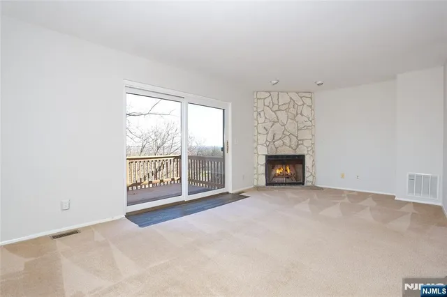 a view of an empty room with a fireplace and a window
