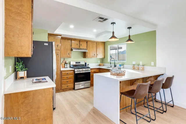 a kitchen with a refrigerator a stove a sink dishwasher with a dining table and chairs