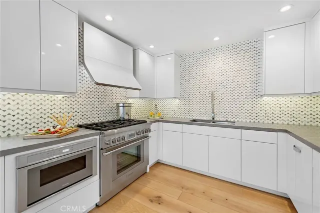 a kitchen with stainless steel appliances granite countertop a sink a stove and wooden cabinets