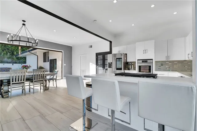 a kitchen with stainless steel appliances a table and chairs in it