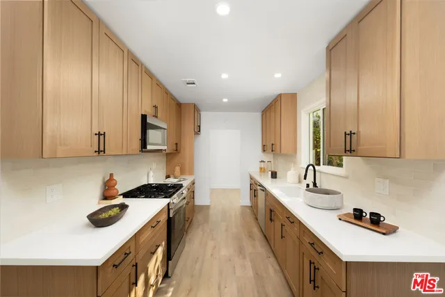 a kitchen with stainless steel appliances a sink stove and cabinets
