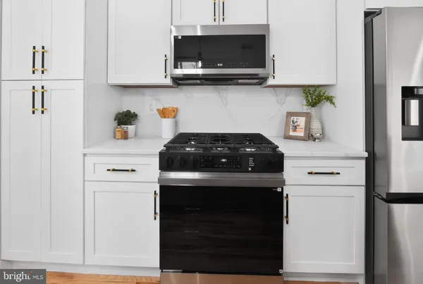 a kitchen with stainless steel appliances granite countertop white cabinets and a stove