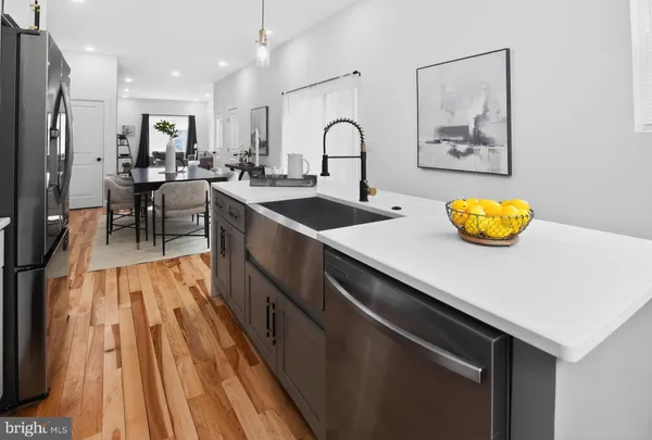 a kitchen with stainless steel appliances granite countertop a stove a sink and a dining table with wooden floor