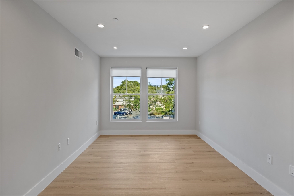 186 Bedford Street, Unit 204 Lexington, MA 02420 - Photo 4 of 10 an empty room with wooden floor and windows