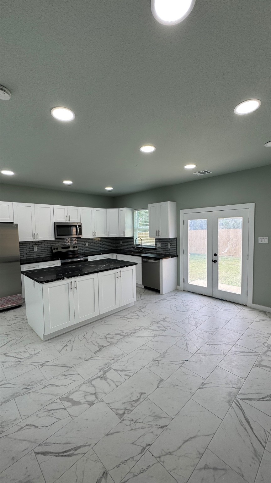 169 South 10th Street Conroe, TX 77301 - Photo 11 of 42 a large white kitchen with kitchen island granite countertop a stove a sink a refrigerator and white cabinets