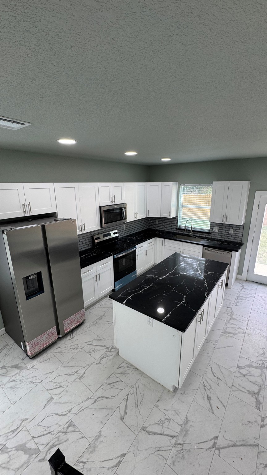 169 South 10th Street Conroe, TX 77301 - Photo 18 of 42 a kitchen with stainless steel appliances a sink a stove a microwave a counter top and cabinets