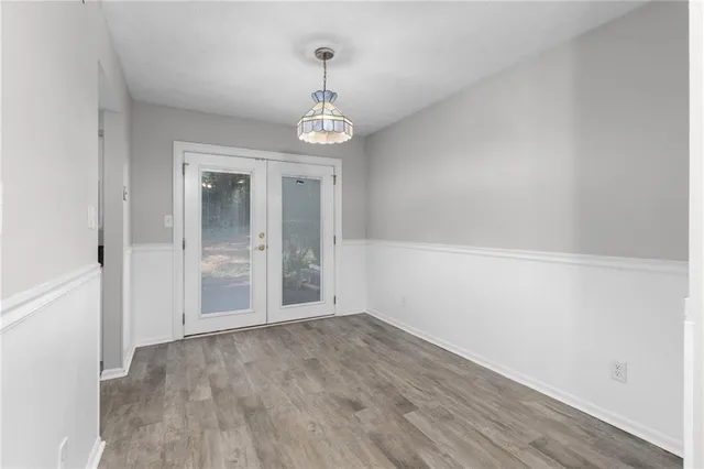 an empty room with wooden floor and chandelier