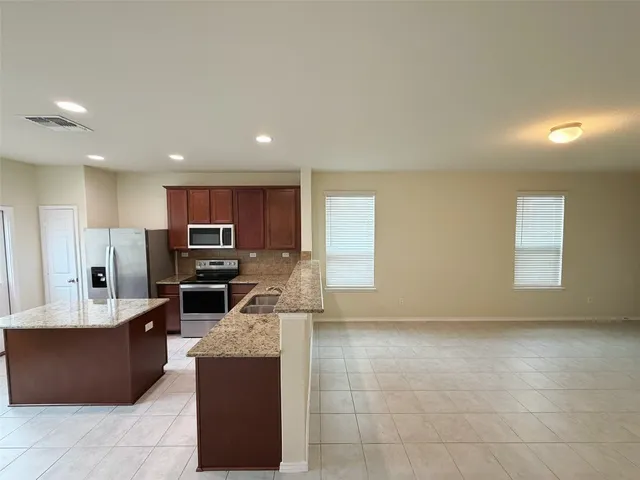 a large kitchen with kitchen island granite countertop a large counter top and stainless steel appliances