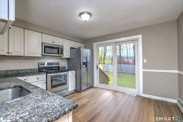 a kitchen with granite countertop a stove a sink and a refrigerator