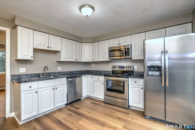 a kitchen with granite countertop a refrigerator stove and microwave