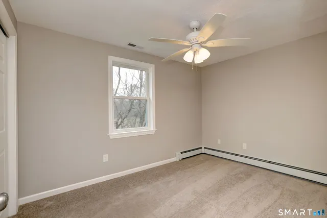 an empty room with a window and a fan