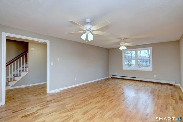 a view of an empty room with window and wooden floor