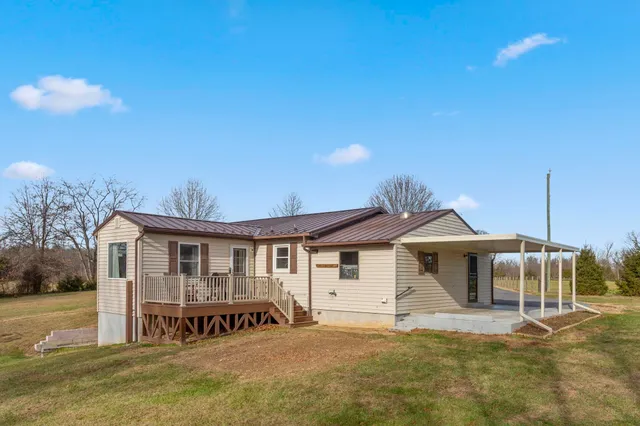a view of a white house with a big yard and large trees