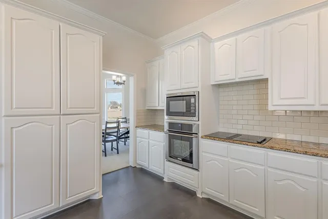 a large white kitchen with a sink and dishwasher a stove top oven with wooden floor