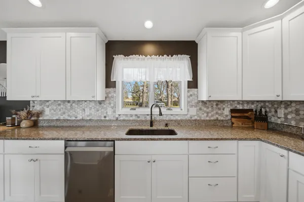 a kitchen with granite countertop white cabinets white appliances and a sink