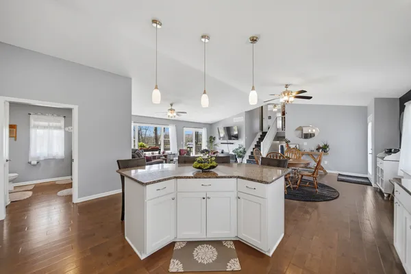 a view of a kitchen with kitchen island granite countertop wooden floor stainless steel appliances and dining table