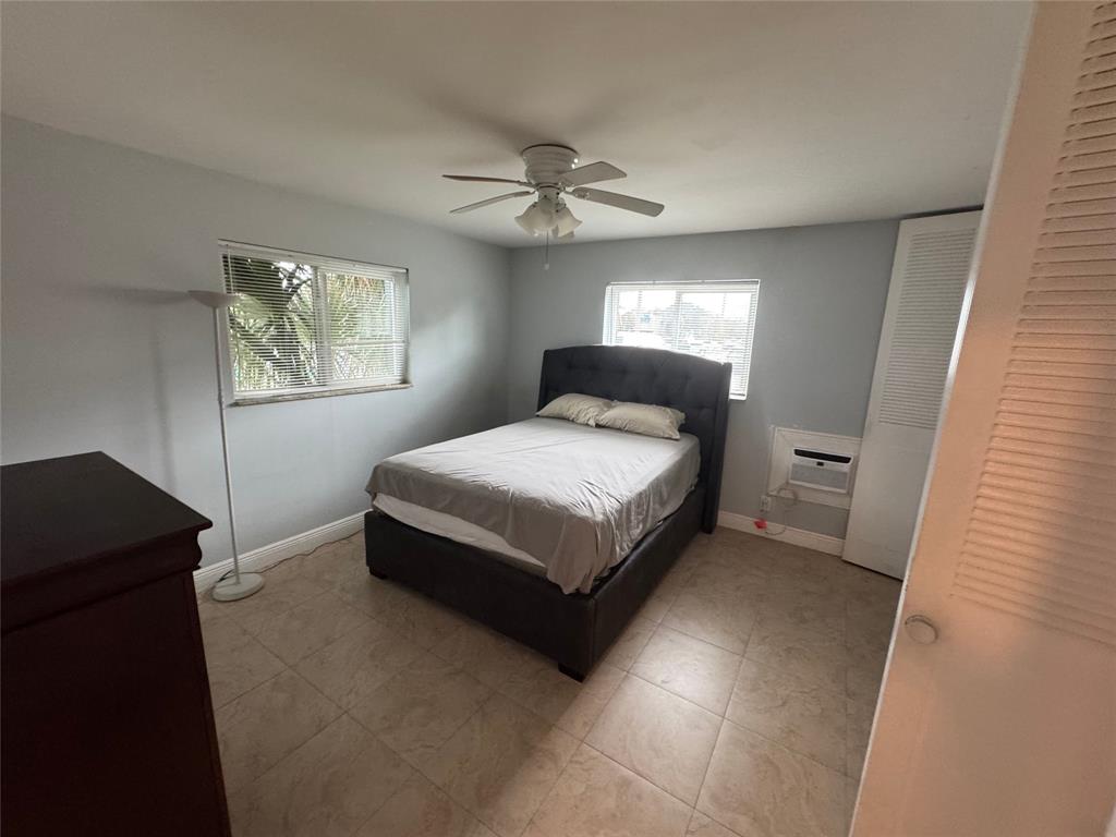 1150 East Sample Road, Unit 101 Pompano Beach, FL 33064 - Photo 13 of 17 a bedroom with a bed and a painting on the wall