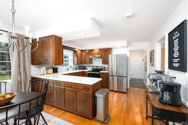 a kitchen with stainless steel appliances granite countertop a refrigerator a sink dishwasher a stove and a dining table with wooden floor