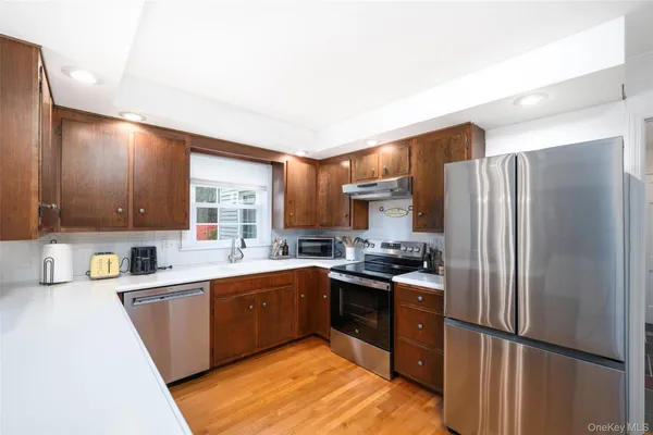 a kitchen with stainless steel appliances granite countertop a refrigerator a sink dishwasher a stove and a refrigerator