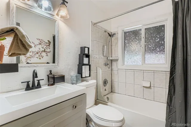 a bathroom with a sink a toilet a mirror a vanity and shower