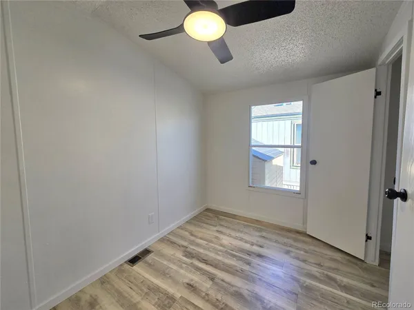 a view of an empty room with window and wooden floor