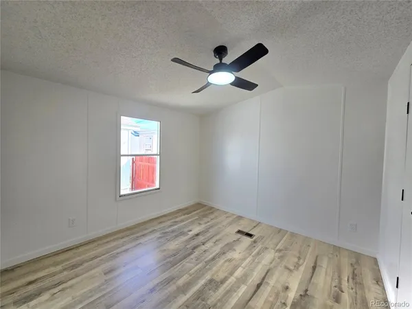 a view of empty room with wooden floor and fan