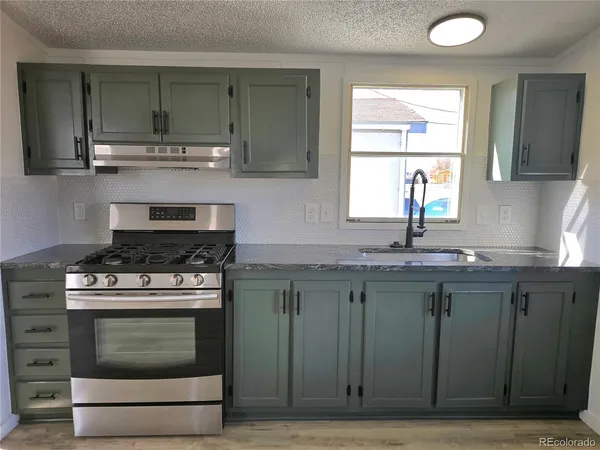 a kitchen with granite countertop a stove a sink and a counter space
