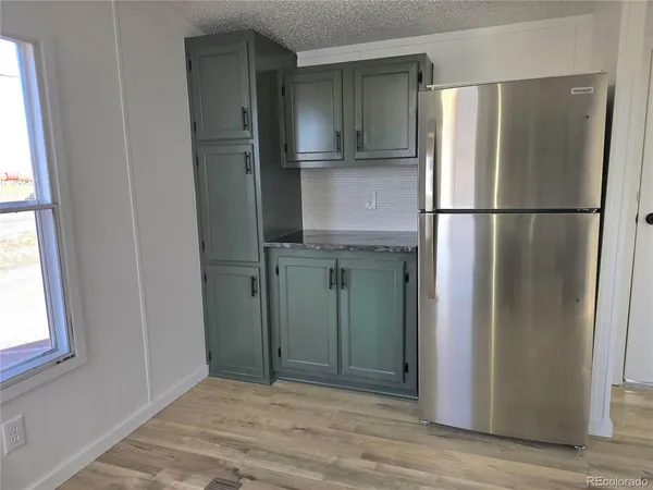 a view of a kitchen with refrigerator and wooden floor