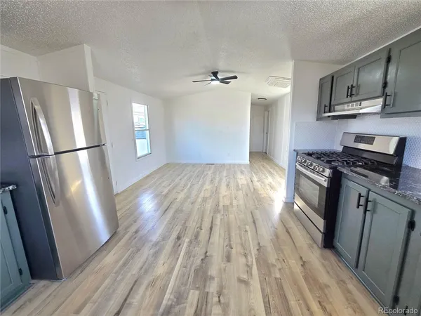 a kitchen with stainless steel appliances a refrigerator stove and wooden floor