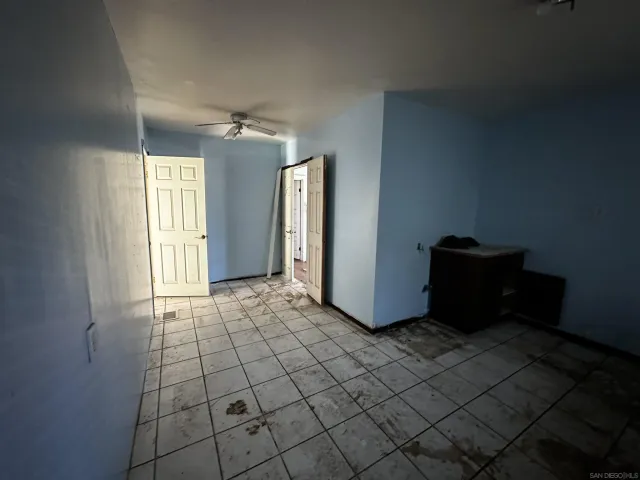 a view of an empty room with window and chandelier fan