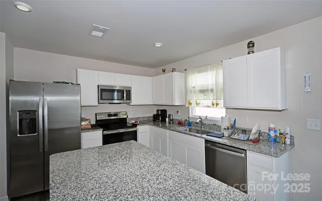 a kitchen with granite countertop a refrigerator sink and wooden cabinets