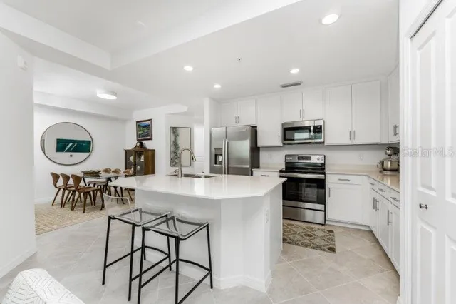 a kitchen with stainless steel appliances kitchen island granite countertop a stove a sink a oven a dining table and chairs with wooden floor