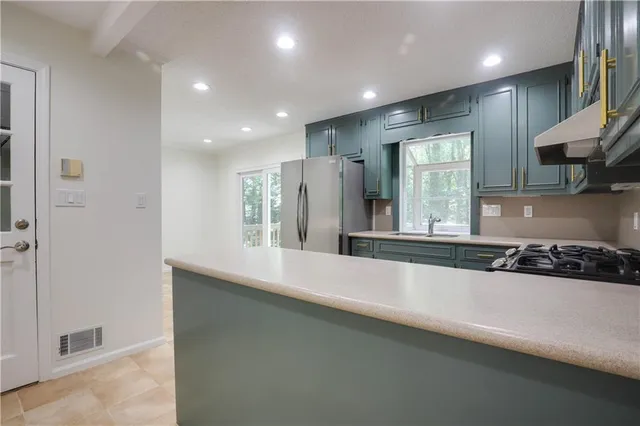 a large kitchen with stainless steel appliances a sink a stove and a refrigerator