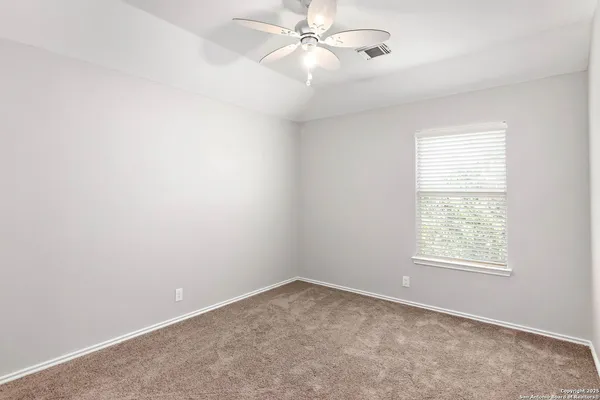 an empty room with windows and fan