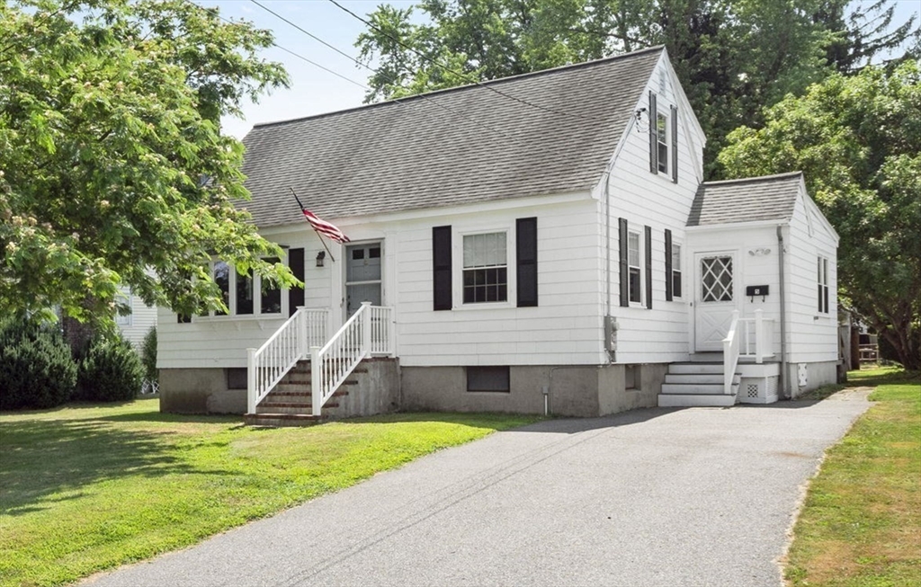 a front view of a house with a yard and trees