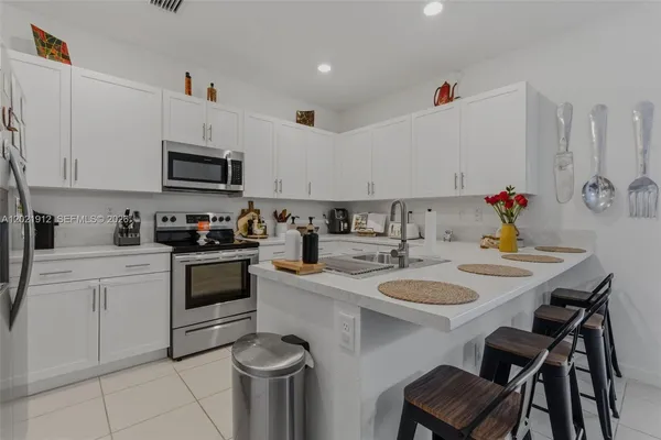 a kitchen with a sink a stove and white cabinets