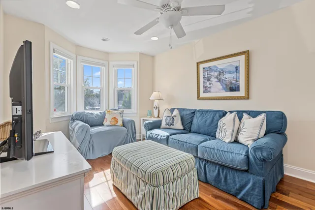 a living room with furniture a flat screen tv and a large window
