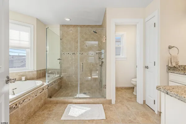 a bathroom with a granite countertop sink a mirror a bathtub and next to a window
