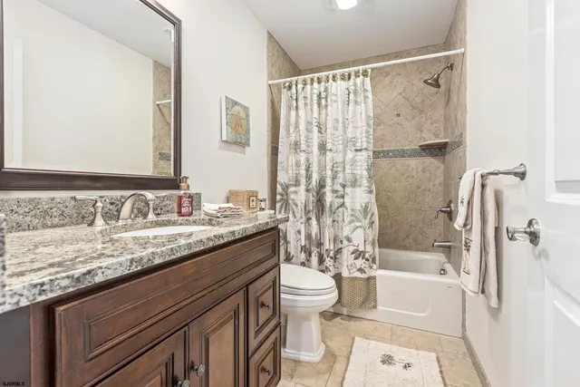 a bathroom with a granite countertop sink a toilet and shower