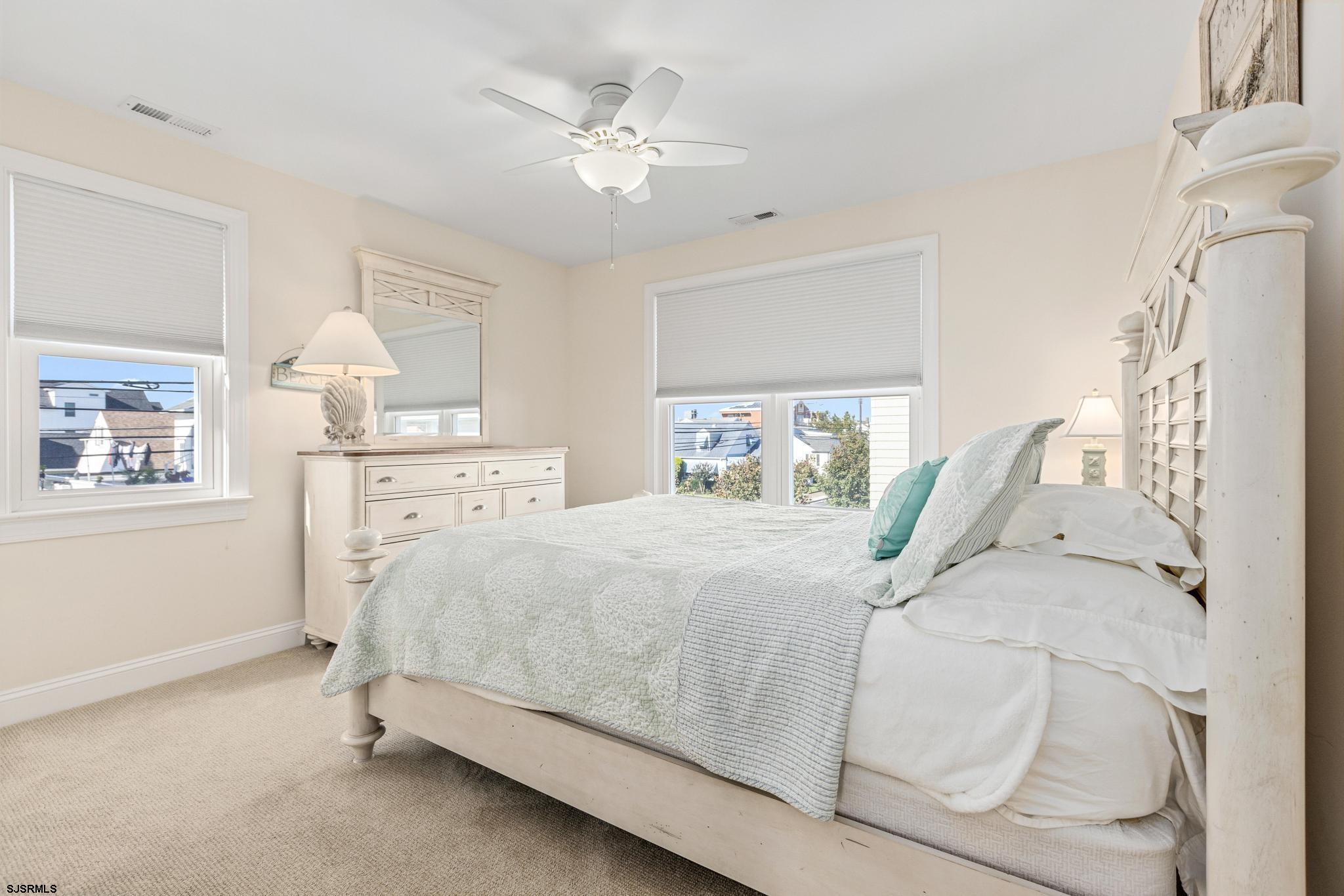 29 North Iroquois Avenue, Unit 6/16/26 FLEXIBLE WITH START DATE Margate City, NJ 08402 - Photo 19 of 40 a bed sitting in a bedroom next to a window and a chandelier