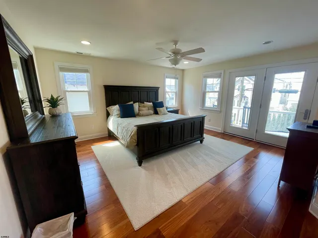 a living room with a bed furniture flat screen tv and wooden floor