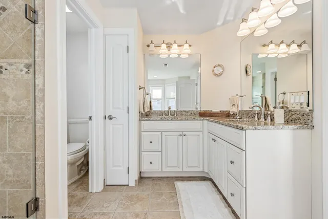 a spacious bathroom with a granite countertop sink a mirror and a shower