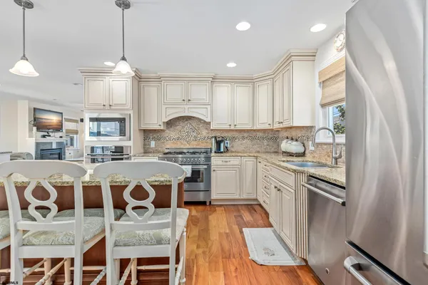 a kitchen with a refrigerator a stove a sink dishwasher and white cabinets with wooden floor