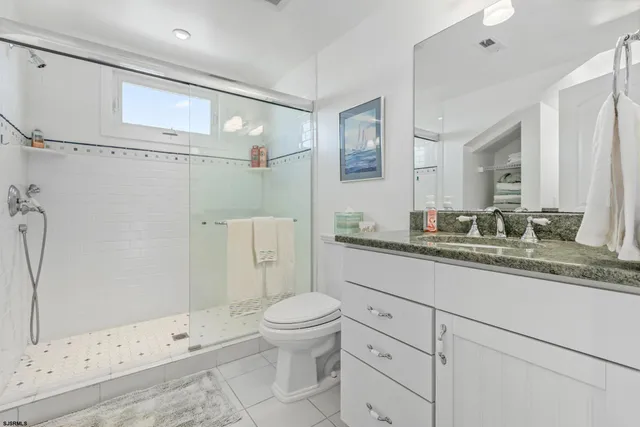 a bathroom with a granite countertop sink a toilet and shower
